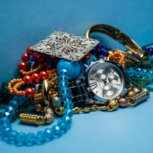 A close-up shot of various colorful jewelry pieces with a stylish wristwatch on blue background.